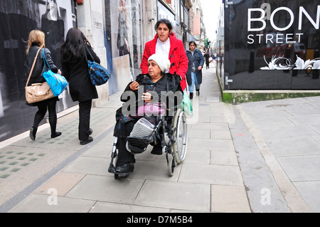 London, England, Vereinigtes Königreich. Frau, Mutter (?) in einem Rollstuhl zu schieben. Bond Street Stockfoto
