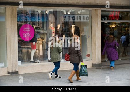 Käufer zu Fuß vorbei an H & M Store auf belebten Hauptstraße in Exeter Devon England UK Stockfoto