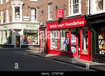 Oxfam und British Heart Foundation Charity High Street Geschäfte In der Innenstadt York North Yorkshire England Großbritannien Vereinigtes Königreich Großbritannien Stockfoto