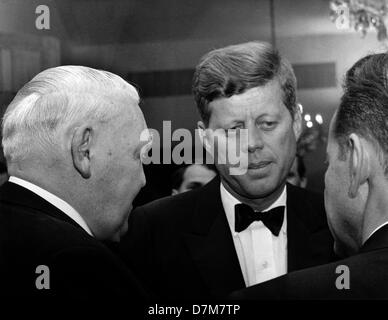 US-Präsident John F. Kennedy (m) spricht mit seinen Gästen bei einem Empfang organisiert zu seinen Ehren im Palais Schaumburg in Bonn am 23. Juni 1963. Hier spricht er mit Bundes-Wirtschaftsminister Ludwig Erhard (l, Rückansicht). Präsident Kennedy war die Bundesrepublik für vier Tage zu Besuch. Stockfoto