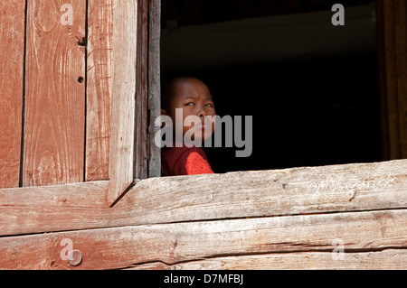 Buddhistischen Novizen schaut aus dem Fenster seines hölzernen Klosters Inle Lake Myanmar (Burma) Stockfoto