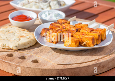 Paneer Tikka Kebab - Tadoori indischer Käse Spieße mit Naan-Brot, Chili-Soße und Gurke und Joghurt Raita. Essen im freien Stockfoto