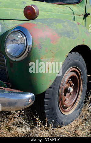 Ein Alter antiken LKW rostet langsam in einem Berg-Feld mit einem Platten Reifen bis zu seinem Untergang zu bezeugen. Stockfoto