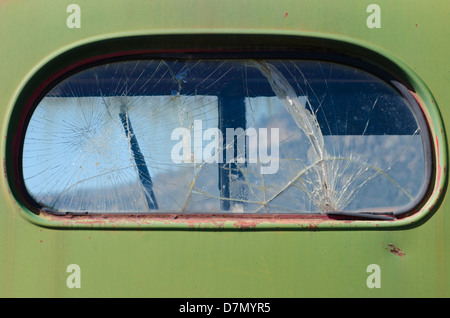 Ein Alter antiken LKW rostet langsam in einem Berg-Feld mit einem hinteren Fenster, das in Hunderten von Glasscherben geknackt ist. Stockfoto