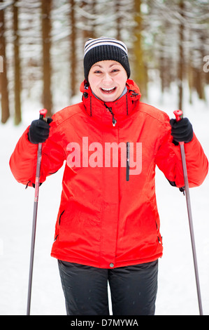 Glückliches Mädchen posiert auf Skiern in den Winterwald. Stockfoto
