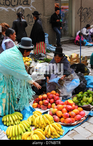 Aymara Dame oder Cholita kauft Obst im Mercado Rodriguez, einem typischen Straßenmarkt in der Nähe des Stadtzentrums La Paz, Bolivien Stockfoto