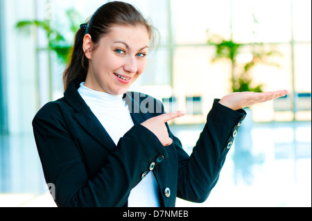 Glückliche junge Frau hält so etwas auf die Palme Ihrer Hand und zeigt einen Finger in ihr Stockfoto