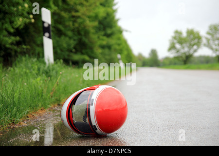 Motorradhelm auf einer nassen Straße Stockfoto