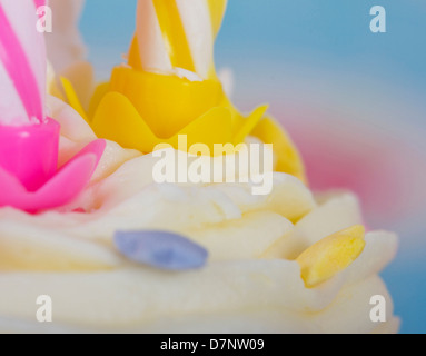 Makroaufnahme von Vereisung auf Cupcake mit zwei Kerzen Sterne Dekorationen blau Hintergrund Stockfoto