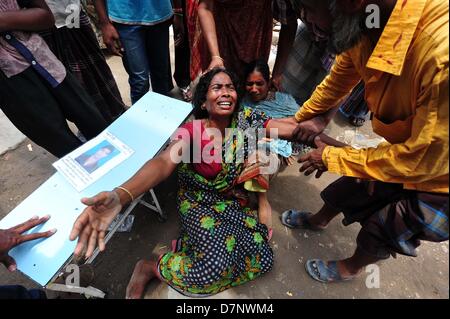 Savar, Bangladesch. 11. Mai 2013. Ein Bangladeshi Familienmitglied Schreie, als sie oben hält das Porträt ihres fehlenden relative, geglaubt, in den Trümmern einer 8-stöckigen Gebäude Einsturz in Savar gefangen zu sein, in der Nähe von Dhaka. Die behandelnden Ärzte ein 'Wunder' Überlebenden zogen von den Ruinen einer eingestürzten Gebäude nach 17 Tagen sagte, dass sie Tat 'große' und hatte mit ihrer Familie wieder vereint. Reshma, 18, eine Näherin gegraben aus aus dem Schutt der Textilfabrik komplex", gab nie auf Hoffnung", aus den Trümmern gerettet werden würde. Stockfoto