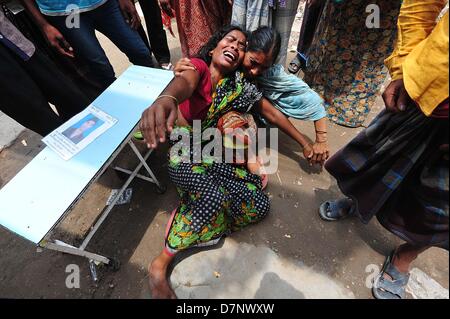 Savar, Bangladesch. 11. Mai 2013. Ein Bangladeshi Familienmitglied Schreie, als sie oben hält das Porträt ihres fehlenden relative, geglaubt, in den Trümmern einer 8-stöckigen Gebäude Einsturz in Savar gefangen zu sein, in der Nähe von Dhaka. Die behandelnden Ärzte ein 'Wunder' Überlebenden zogen von den Ruinen einer eingestürzten Gebäude nach 17 Tagen sagte, dass sie Tat 'große' und hatte mit ihrer Familie wieder vereint. Reshma, 18, eine Näherin gegraben aus aus dem Schutt der Textilfabrik komplex", gab nie auf Hoffnung", aus den Trümmern gerettet werden würde. Stockfoto