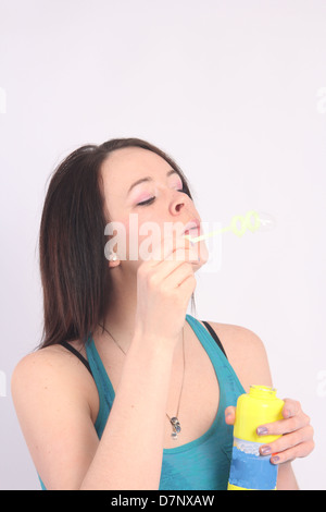 Sehr hübsche junge Frau bläst Seifenblasen durch einen kleinen Zauberstab. Stockfoto