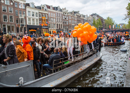 Jährlichen Königinnentag in den Niederlanden. Bootskorso in den Grachten von Amsterdam, Altstadt. Menschen in Orange gekleidet. Amsterdam Stockfoto