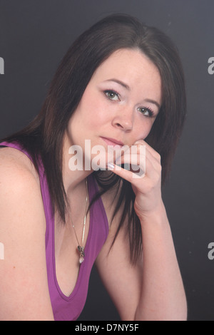 Schöne junge Frau trägt ein lila Singulett gegen einen schwarzen Hintergrund Stockfoto