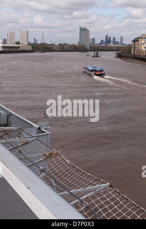 Der Fluss Thames, nr Greenwich, London, UK. 11. Mai 2013. Ein Thames Clipper Kreuzfahrt vorbei an HMS Illustrious, die Royal Navy Hubschrauber und Commando Träger mit dem Shard und City of London im Hintergrund. Während des Besuchs in London, des 70. Jahrestags des "Battle of the Atlantic" genommen. Vor Anker auf der Themse neben Greenwich am Samstag, 11. Mai 2013. Bildnachweis: Craig Buchanan /Alamy Live-Nachrichten Stockfoto