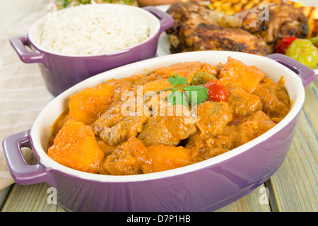 Lamm und Süßkartoffel-Erdnuss-Eintopf mit Reis serviert. Jerk Chicken. Karibik und westafrikanischen traditionelle Gerichte. Stockfoto