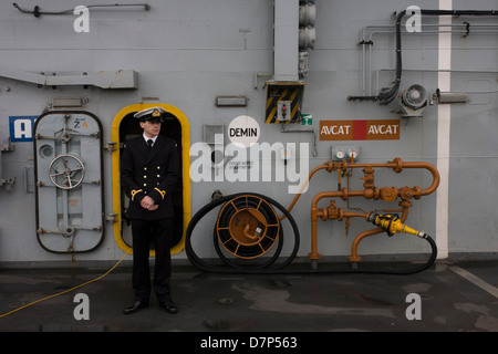 Ein Student Offizier vom Dienst auf der oberen deck während einer Tour durch die breite Öffentlichkeit an Bord Flugzeugträger der Royal Navy HMS Illustrious während eines öffentlichen Open-Tages in Greenwich. Illustrious angedockt an der Themse, so dass die Steuern zahlenden öffentlichen um den Decks vor seiner bevorstehenden Decommisioning zu erkunden. Navy Personal half mit dem PR-Event über die Mai Wochenende, historisch der Heimat England Flotte. Stockfoto