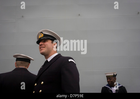 Student Offiziere und ein Matrose Bewertung im Dienst unter den riesigen Rumpf ihres Schiffes während einer Tour durch die breite Öffentlichkeit an Bord Flugzeugträger der Royal Navy HMS Illustrious während eines öffentlichen Open-Tages in Greenwich. Illustrious angedockt an der Themse, so dass die Steuern zahlenden öffentlichen um den Decks vor seiner bevorstehenden Decommisioning zu erkunden. Navy Personal half mit dem PR-Event über die Mai Wochenende, historisch der Heimat England Flotte. Stockfoto