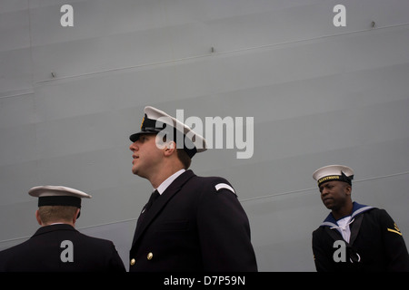 Student Offiziere und ein Matrose Bewertung im Dienst unter den riesigen Rumpf ihres Schiffes während einer Tour durch die breite Öffentlichkeit an Bord Flugzeugträger der Royal Navy HMS Illustrious während eines öffentlichen Open-Tages in Greenwich. Illustrious angedockt an der Themse, so dass die Steuern zahlenden öffentlichen um den Decks vor seiner bevorstehenden Decommisioning zu erkunden. Navy Personal half mit dem PR-Event über die Mai Wochenende, historisch der Heimat England Flotte. Stockfoto