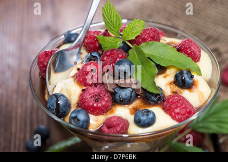 Pudding-Dessert mit Schokoladensauce und frischen Beeren auf hölzernen Hintergrund Stockfoto