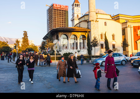 Menschen überqueren Skanderbeg-Platz mit Ethem Bey-Moschee im Hintergrund. Tirana, Albanien Stockfoto