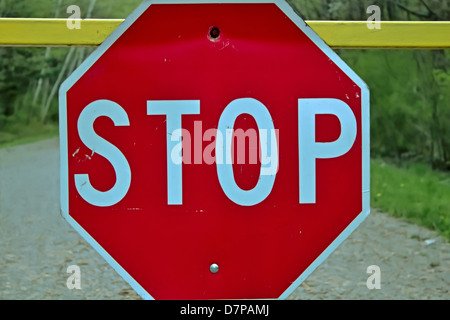 Stop! Stop-Schild an gelber Balken aufgehängt. Stockfoto