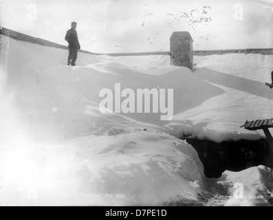 Dieses historische Foto zeigt ein schneebedecktes Haus in *Kiandra*, Australien, aufgenommen im August 1900. Das Bild zeigt die dicken Schneewehungen rund um das Haus und zeigt die Winterbedingungen der Gegend während des frühen 20. Jahrhunderts. Stockfoto