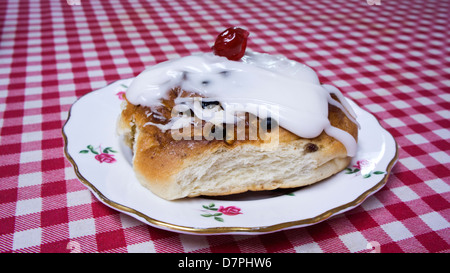 Geeiste Johannisbeeren Brötchen mit Red Cherry auf einer Rosenknospe verziert-Platte auf eine rot-weiße aufgegebenes Tischdecke Stockfoto