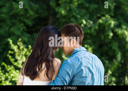 Horizontale Foto eines jungen Erwachsenen paar berühren Stirn an Stirn mit grünen Bäumen im Hintergrund Stockfoto