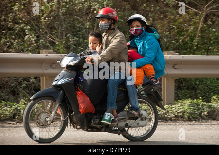 Horizontale Porträt eine vierköpfige Familie mit Koffer und Taschen auf einem Moped nach Hause für Tet, vietnamesisches Neujahr. Stockfoto