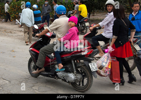 Horizontale Porträt ein Vater und seine Tochter fahren auf der Straße auf einem Moped in Hanoi. Stockfoto