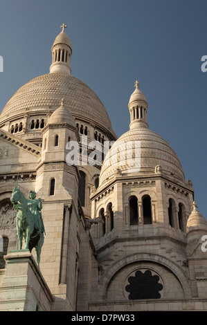 Die hoch aufragenden weißen Kuppeln der Basilika Sacré-Coeur auf dem Montmartre. Über dem Portikus steht ein Reiterstandbild der Jeanne d ' Arc. Paris, Frankreich. Stockfoto