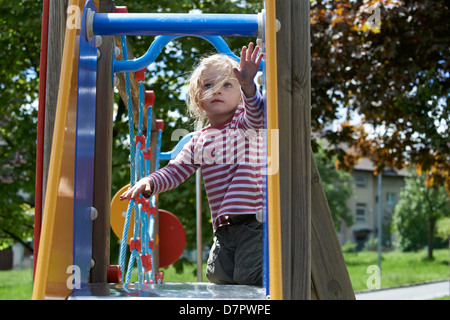 Blonde Mädchen Kind gleitende Folie auf einem Spielplatz Stockfoto