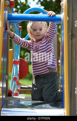 Blonde Mädchen Kind gleitende Folie auf einem Spielplatz Stockfoto