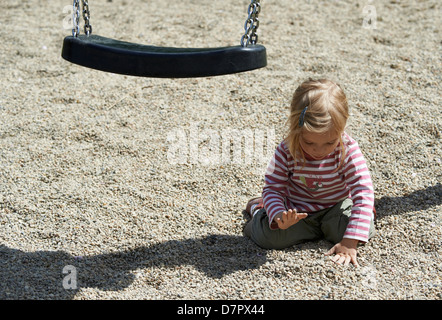 Blond blaue Augen Kind Baby Mädchen zwei Jahre alt spielt im Freien mit Steinen und Kieselsteine auf Spielplatz Stockfoto