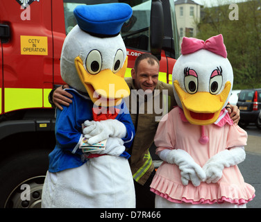 Donald und Daisy Duck posiert mit einem Feuerwehrmann bei der jährlichen Entenrennen der Paisley in Schottland Stockfoto