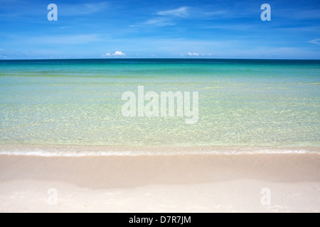 Welle des Meeres am Sandstrand gegen blauen Himmel Stockfoto