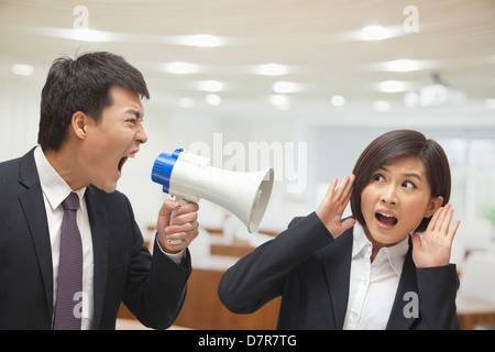 Geschäftsmann in Megaphon durch die Geschäftsfrau Ohr sprechen Stockfoto