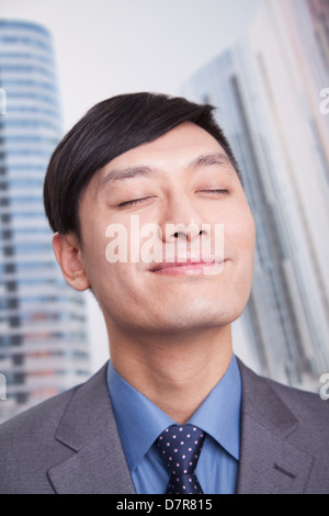 Junger Geschäftsmann mit geschlossenen Augen und Kopf zurück Lächeln, Porträt Stockfoto