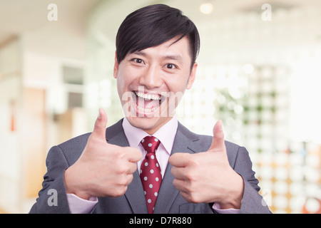 Junge Unternehmer geben die Daumen nach oben Zeichen, Porträt Stockfoto