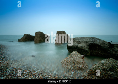 Langzeitbelichtung von konkreten Felsbrocken im Meer Stockfoto