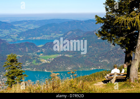 Senior österreichisches Ehepaar auf einer Bank sitzen und Blick auf eine schöne Aussicht von einem Berg Stockfoto