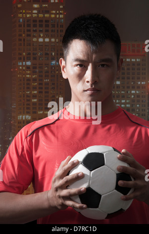 Fußballspieler mit Ball, Brust mit Hochhaus im Hintergrund Stockfoto