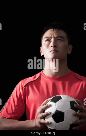 Fußballspieler mit Ball, Brust, schwarzer Hintergrund Stockfoto