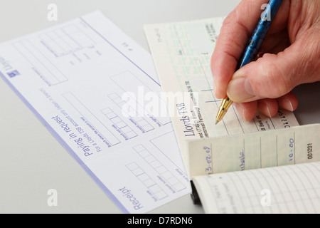 Frau Rentner Geld sparen Schreiben einer Lloyds joint account Check-in eine Bank auf eine Zahlstelle in Credit slip zu bezahlen. England Großbritannien Großbritannien Stockfoto