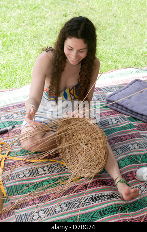 Junge Frau spinnt einen Korb aus Schilf Stockfoto