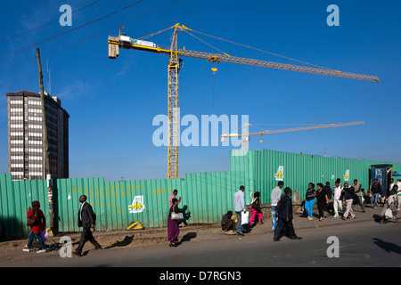 Menschen zu Fuß vorbei an einer großen Baustelle, Addis Abeba, Äthiopien. Stockfoto