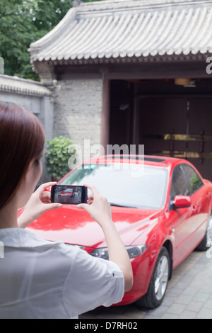 Junge Frau, die ein Bild von ihrem Auto Stockfoto