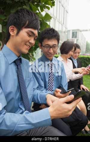 Junge Geschäftsleute, die ihre Handys überprüfen Stockfoto