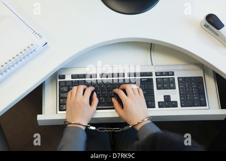 Junge Geschäftsfrau Handschellen an ihrem Bürostuhl direkt über Stockfoto